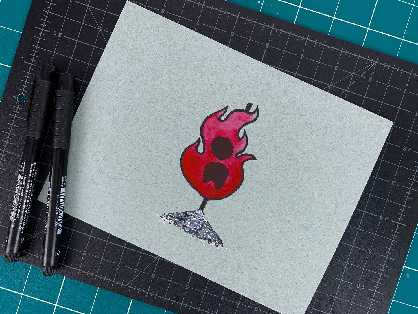 Studio shot of an original illustration of a burning flame engulfing a torso of a witch that's been tied to a stake and ashes below. Made using ink, watercolor, and gouache.