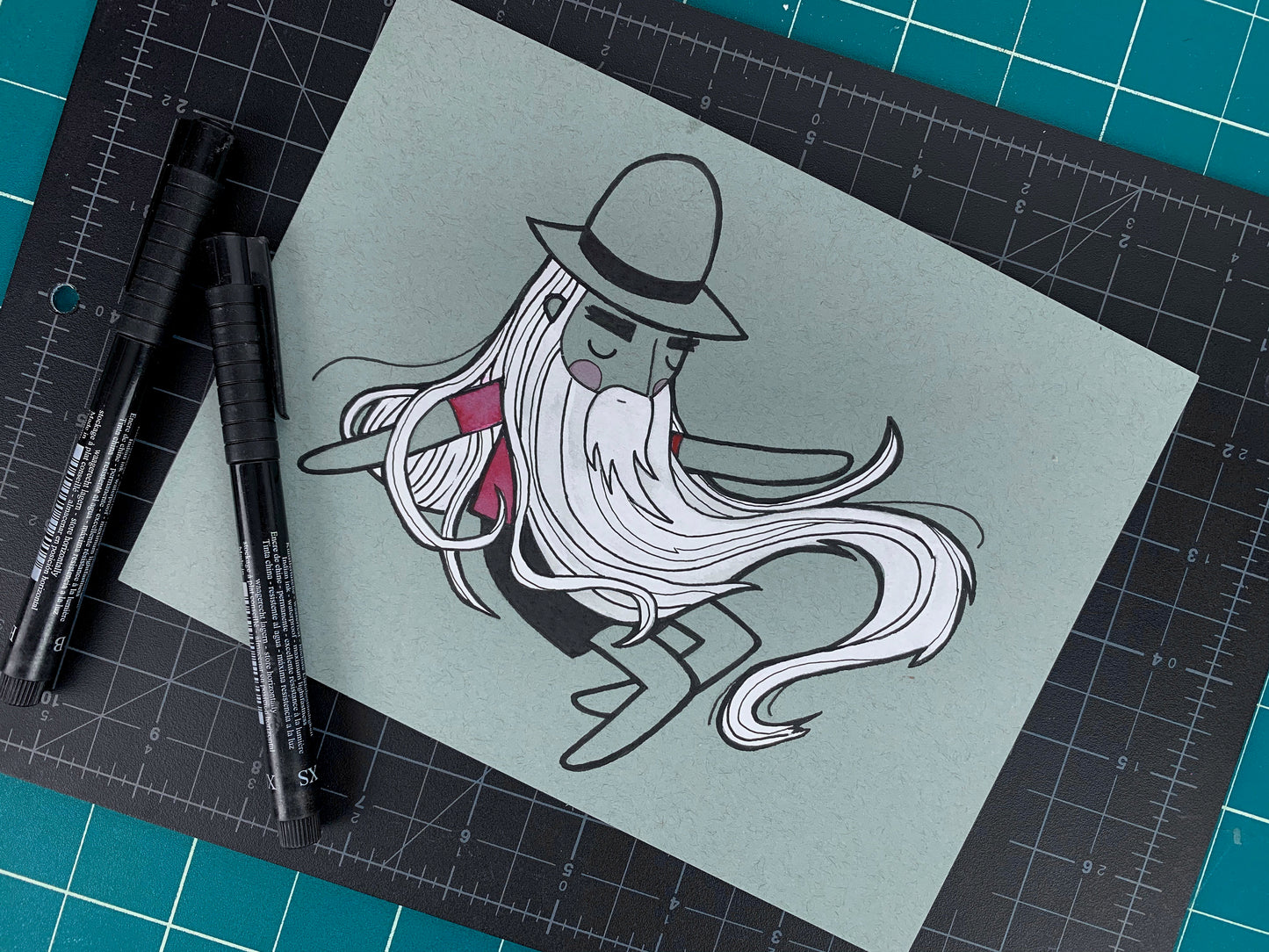 Studio shot of an original illustration of a sleeping Rip Van Winkle like man with a long white beard. Made using ink, watercolor, and gouache.