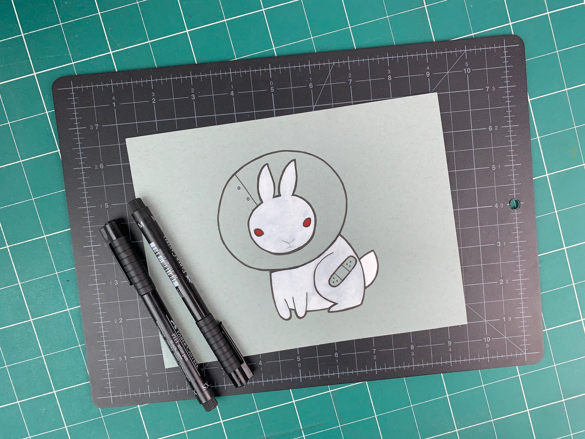 Studio shot of an original illustration of a white rabbit (bunny) wearing a cone collar (cone of shame) with a band-aid over an injurred leg. Made using ink, watercolor, and gouache.