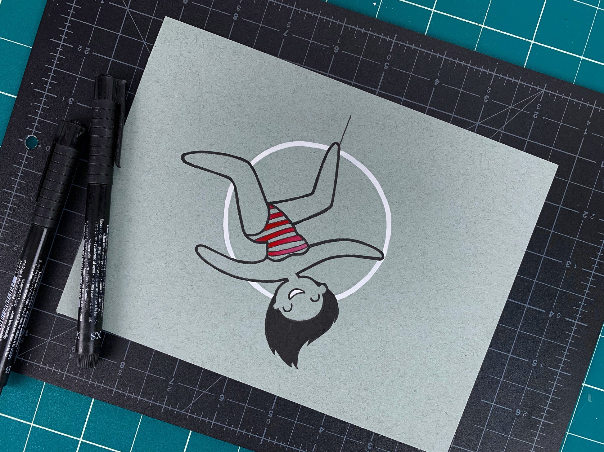 Studio shot of an original illustration of an acrobatic circus performer lady inside of an aerial hoop or aerial ring. Made using ink, watercolor, and gouache.