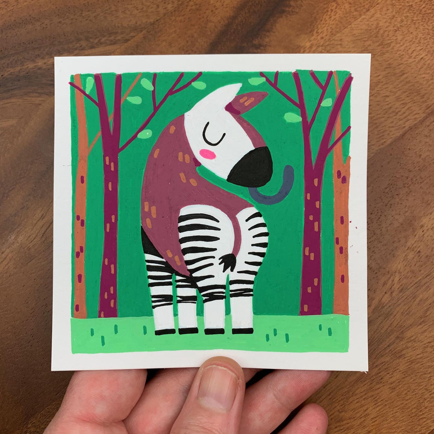 Original artwork of a cute okapi looking back over it's should with it's long tongue sticking out. Materials used: Uni-Posca paint markers.