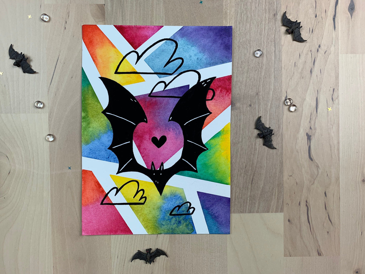 Original artwork depicting a colorful geometric watercolor and gouache painting of a bat.