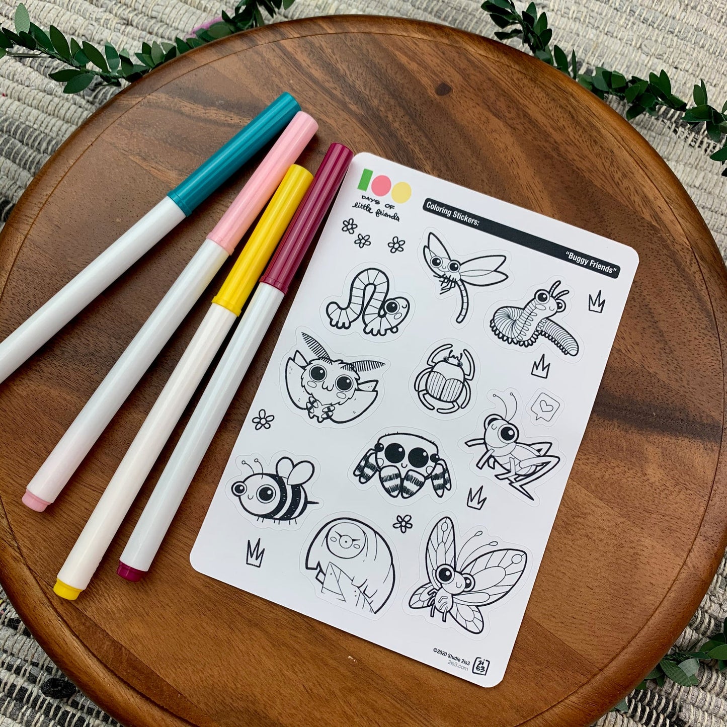 Markers and a sticker sheet with 10 little animal stickers on it. A Dragonfly, Millipede, Inchworm, Beetle, Moth, Spider, Grasshopper, Bee, Tardigrade, and Butterfly.