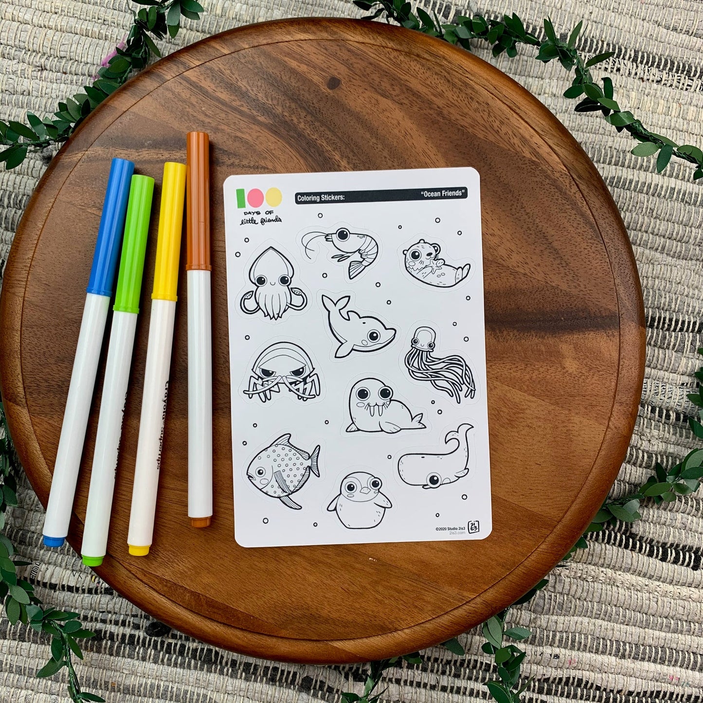 Markers and a sticker sheet with 10 little animal stickers on it. A Squid, Shrimp, Otter, Dolphin, Isopod, Walrus, Jellyfish, Opah, Penguin, and Whale.