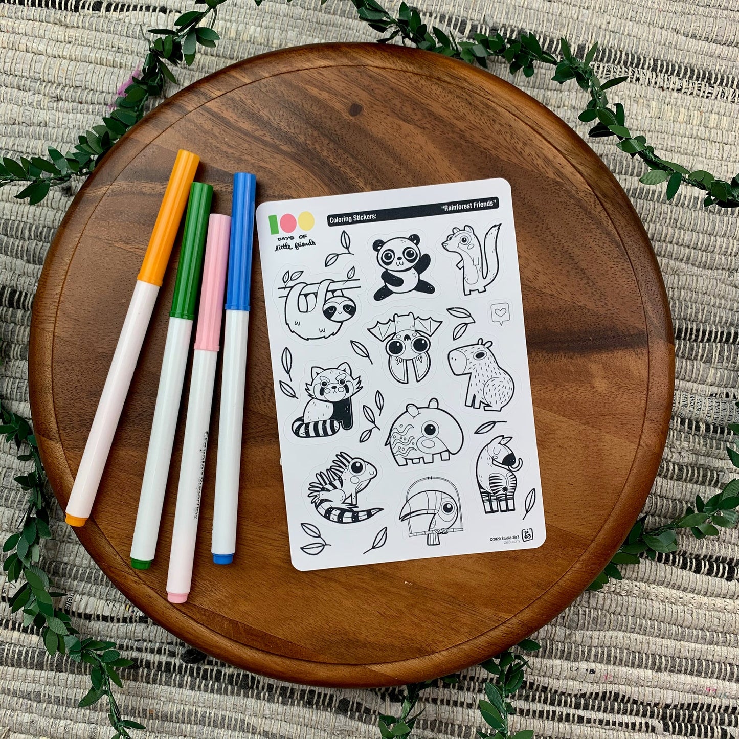 Markers and a sticker sheet with 10 little animal stickers on it. A Panda, Sloth, Mongoose, Bat, Red Panda, Capybara, Tapir, Iguana, Toucan, and Okapi.