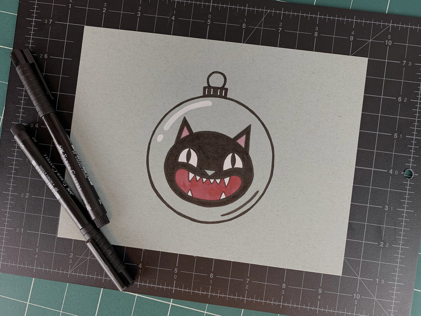 Studio shot of an original illustration of a vintage looking screaming cat inside of a glass ornament, like a Halloween decoration. Made using ink, watercolor, and gouache.