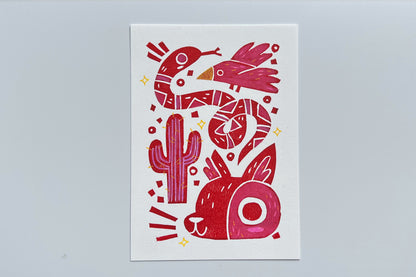 Red ink block print of a bird, snake, cactus, and coyote with colored pencil and POSCA pen coloring.