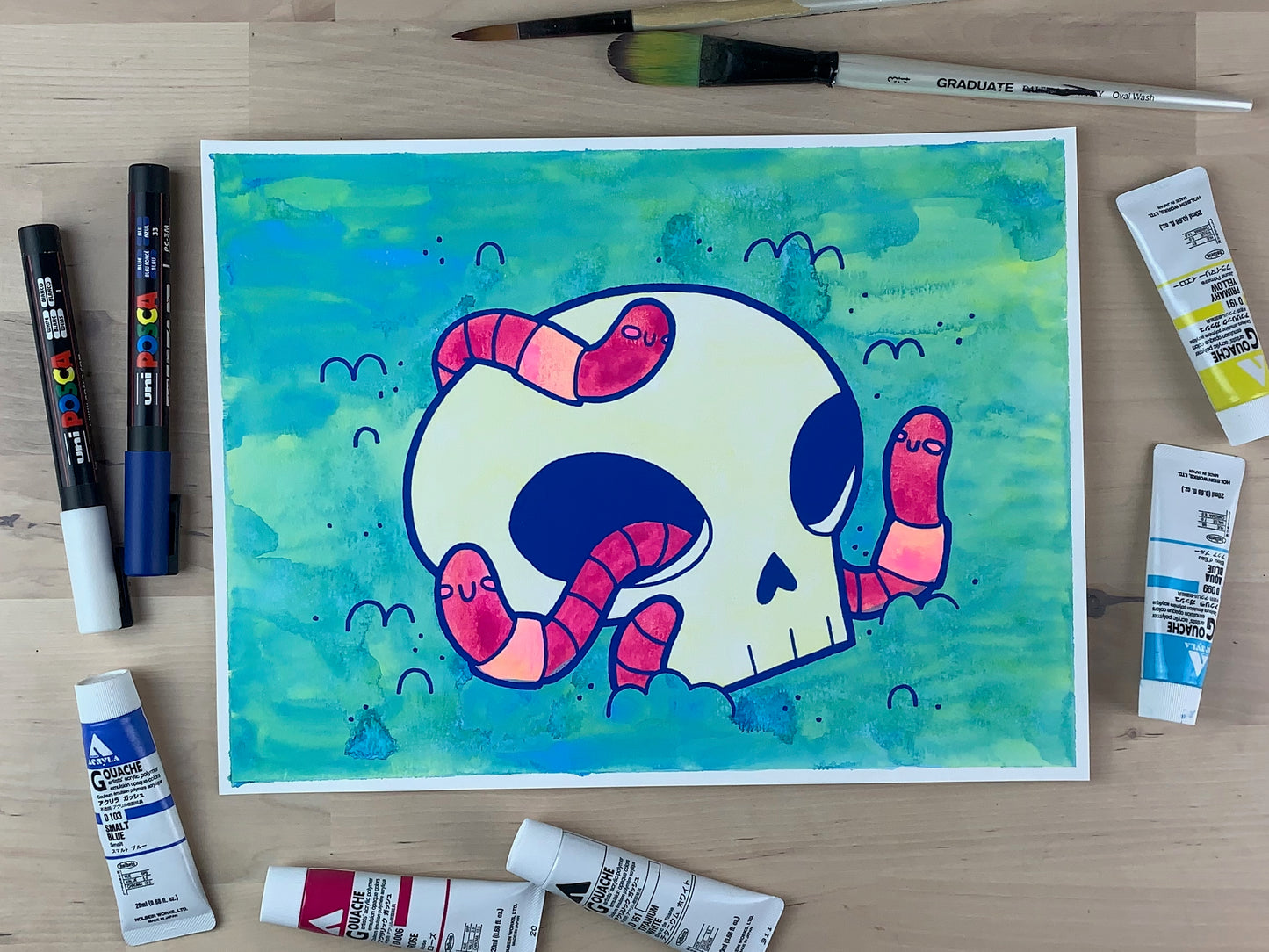 Painting of a skull in the dirt with three pink worms crawling around it.