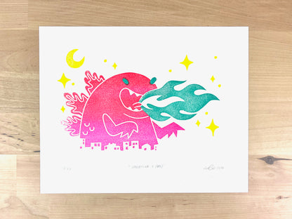 Original art print by Amber Orenstein. Relief print of a pink Japanese kaiju monster roaring with flames while destroying a city.