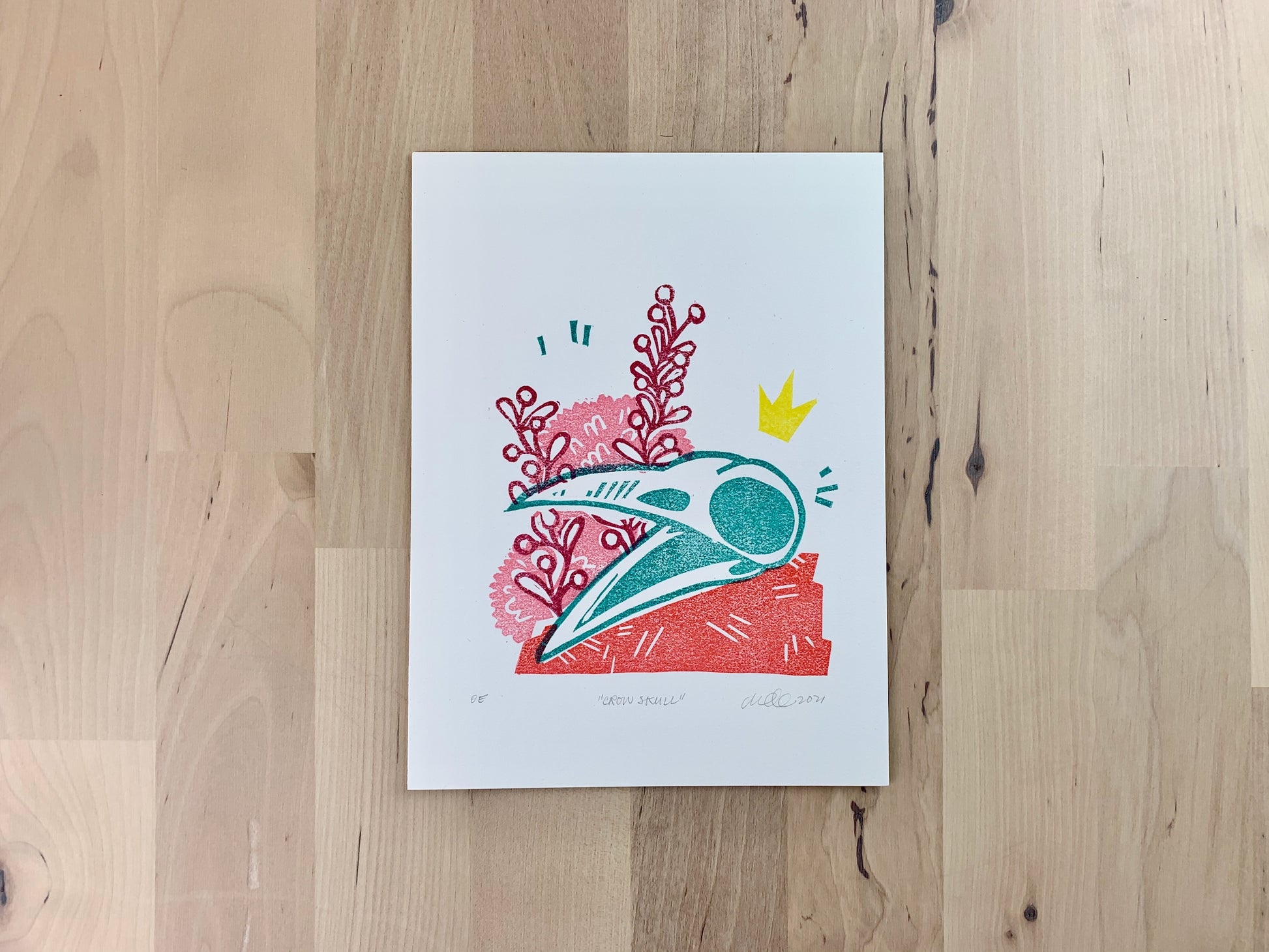 Original art print by Amber Orenstein. A relief print of a crow skull with crown and floral accents.
