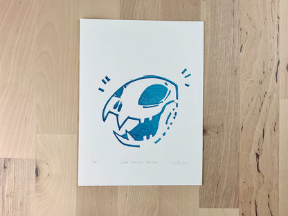 Original art test print by Amber Orenstein. Block print of a blue lion skull.