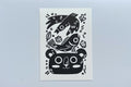 Black ink block print of a bird, fish, leaves, berry, acorn, and bear.