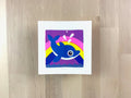 Risograph print of an illustration of a cute dolphin jumping out of the water with a rainbow behind it.
