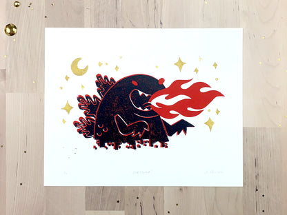 Original limited edition #3 art print by Amber Orenstein. Two color, red and black, reduction block print of a Japanese kaiju monster roaring with flames while destroying a city with gold stars and moon.