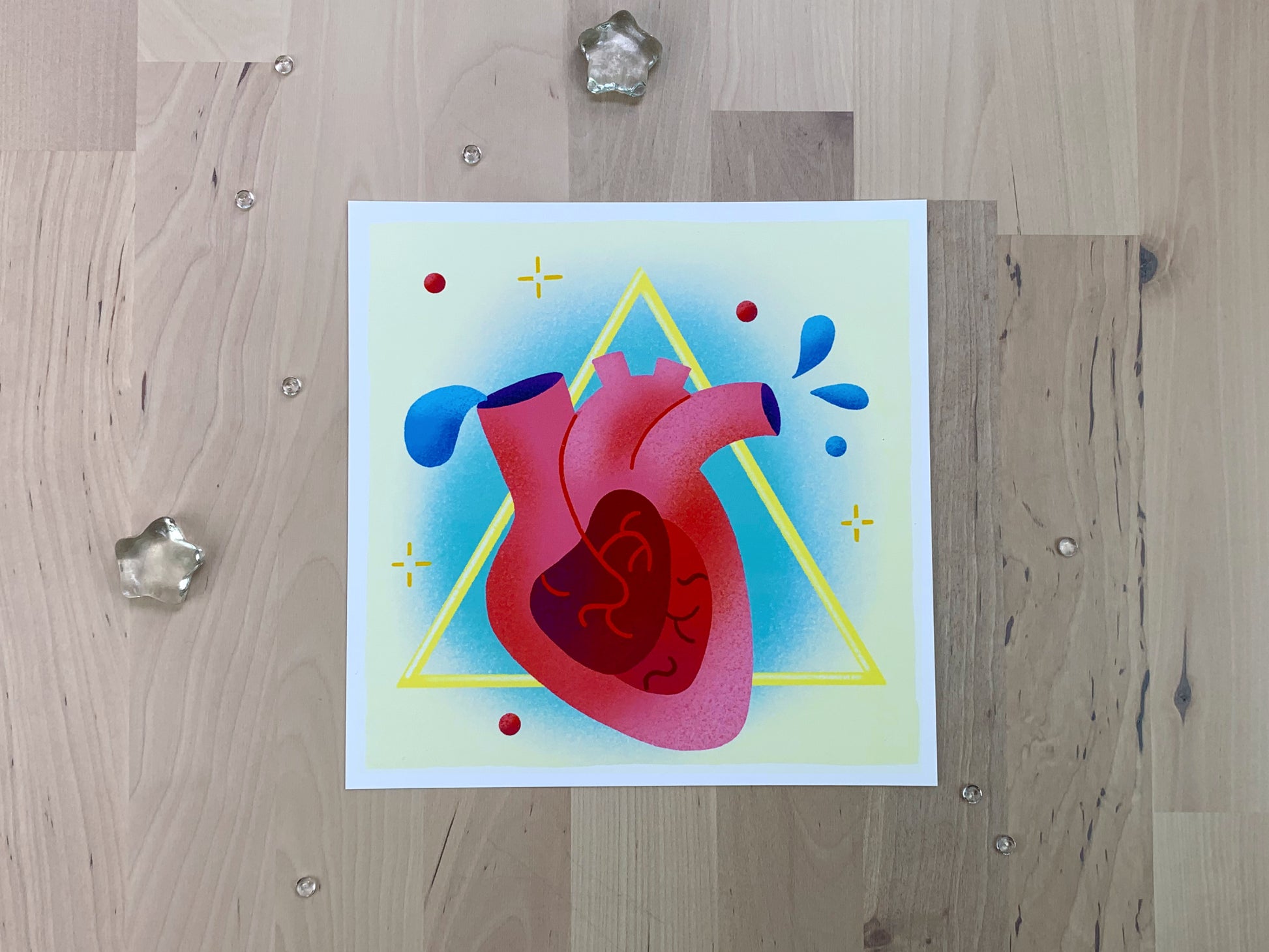 An illustration of a heart with blue blood drops in front of a yellow triangle shape.