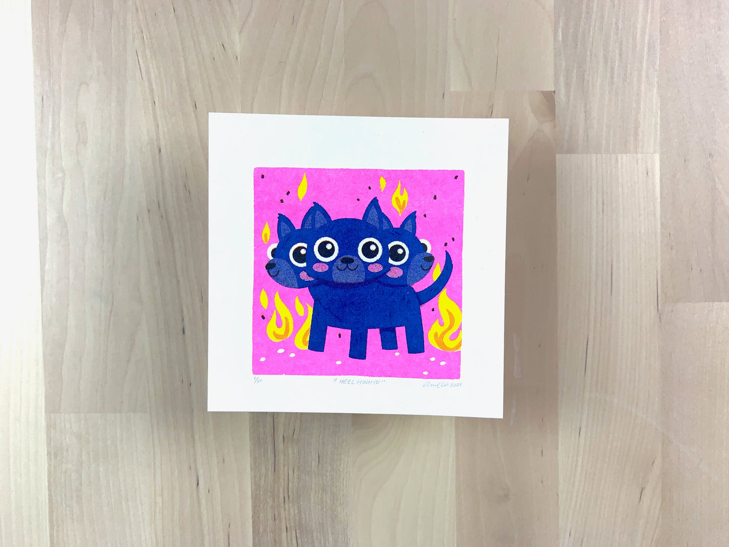 Risograph print of a cute blue three headed dog (Cerberus) illustration on a neon pink background with flames.