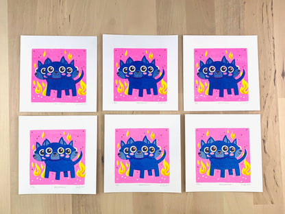 Six Risograph prints of a cute blue three headed dog (Cerberus) illustration on a neon pink background with flames showing the unique variations.