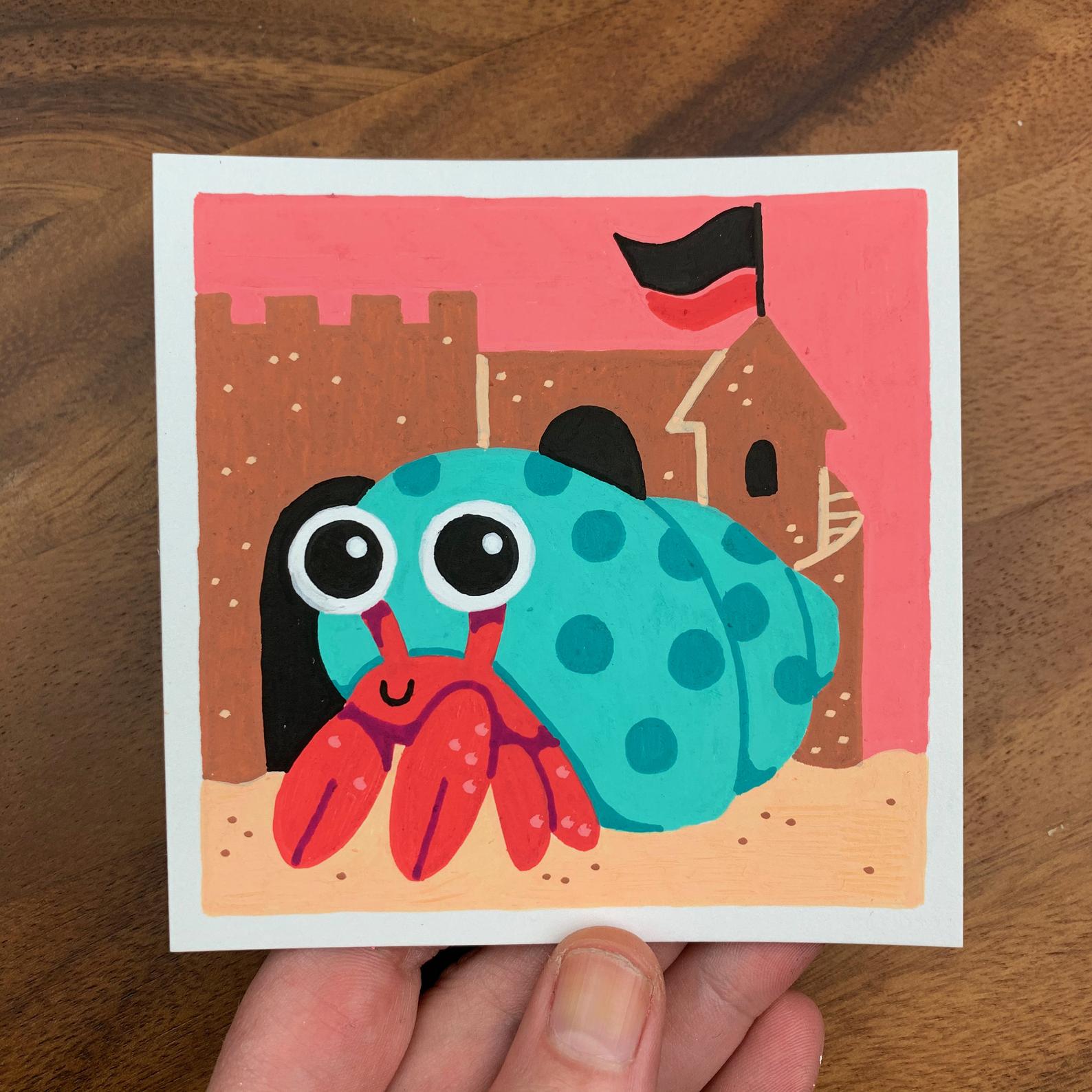 Original artwork of a cute hermit crab in front of a sand castle. Materials used: Uni-Posca paint markers.