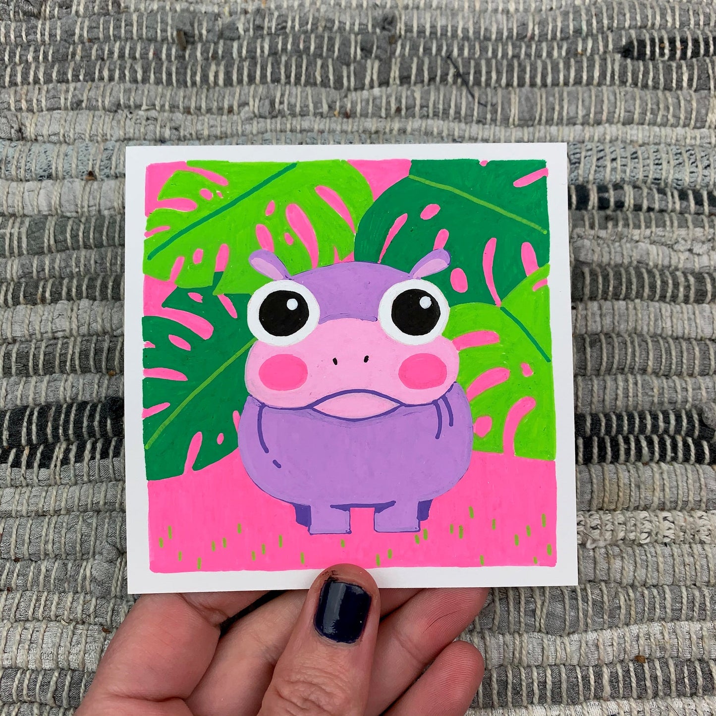 Original artwork of a cute purple hippopotamus in front of some green monstera plants on a pink background. Materials used: Uni-Posca paint markers.