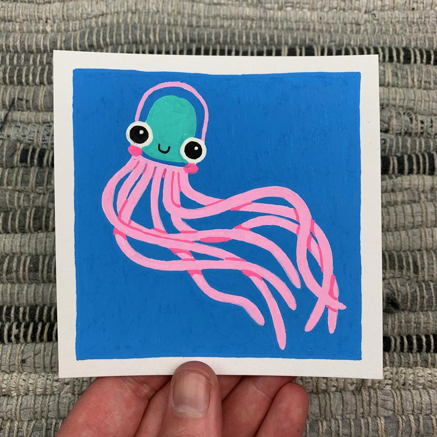 Original artwork of a cute pink jellyfish floating on a blue background. Materials used: Uni-Posca paint markers.