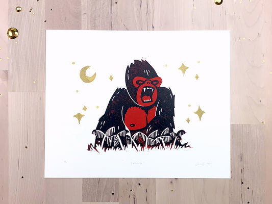 Original limited edition #1 art print by Amber Orenstein. Two color, red and black, reduction block print of a King Kong roaring on his jungle island home with gold stars and moon.