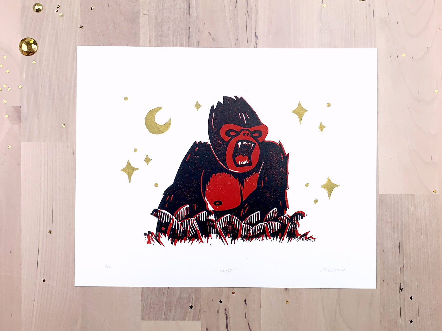 Original limited #5 edition art print by Amber Orenstein. Two color, red and black, reduction block print of a King Kong roaring on his jungle island home with gold stars and moon.