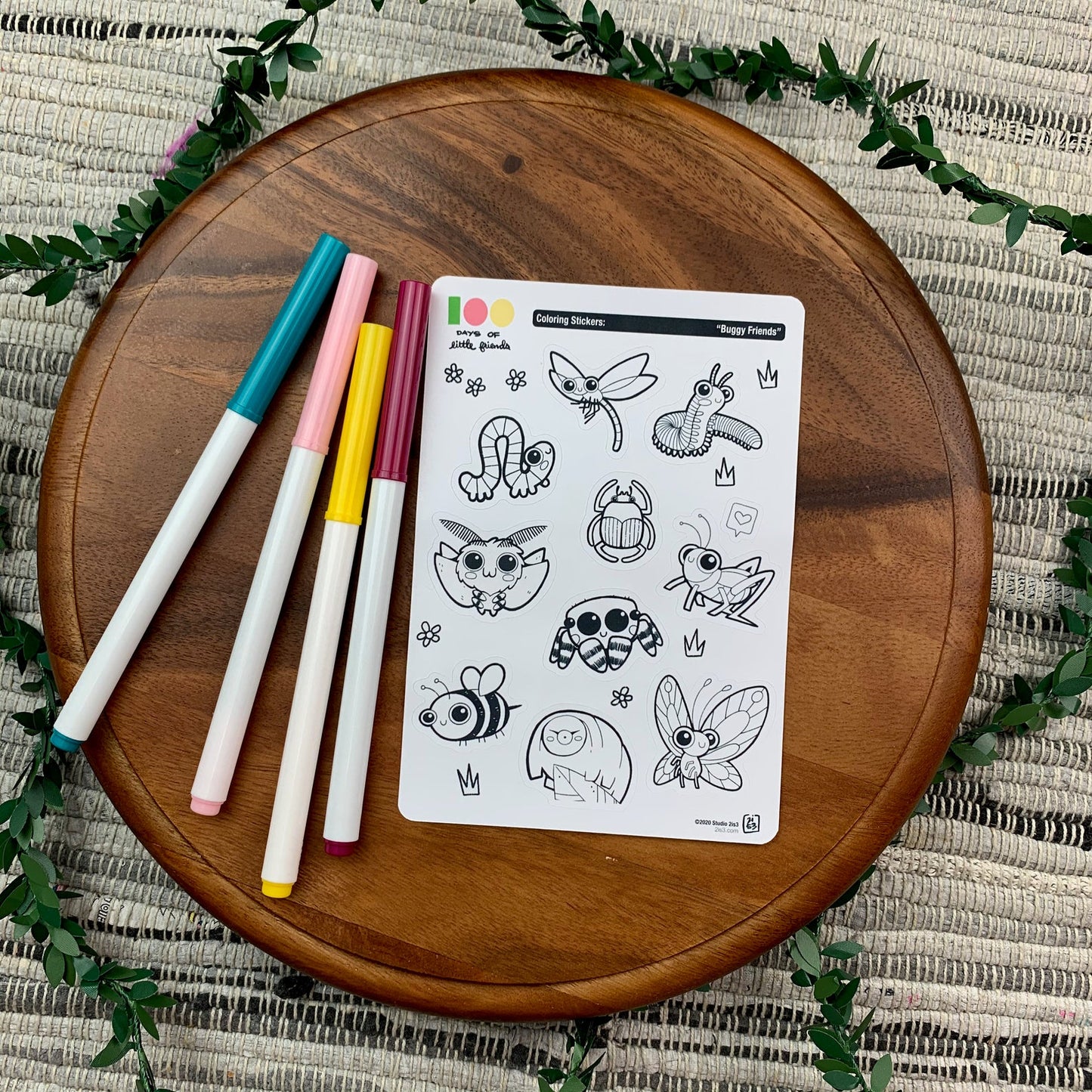 Markers and a sticker sheet with 10 little animal stickers on it. A Dragonfly, Millipede, Inchworm, Beetle, Moth, Spider, Grasshopper, Bee, Tardigrade, and Butterfly.