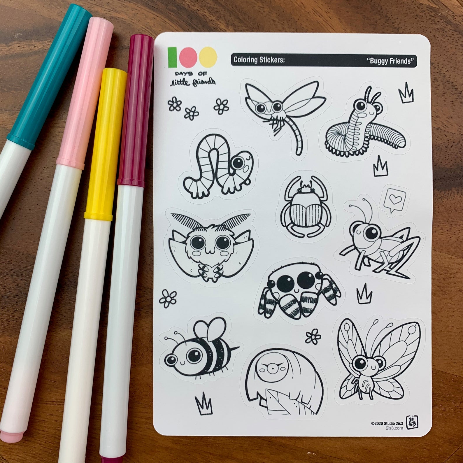 Markers and a sticker sheet with 10 little animal stickers on it. A Dragonfly, Millipede, Inchworm, Beetle, Moth, Spider, Grasshopper, Bee, Tardigrade, and Butterfly.