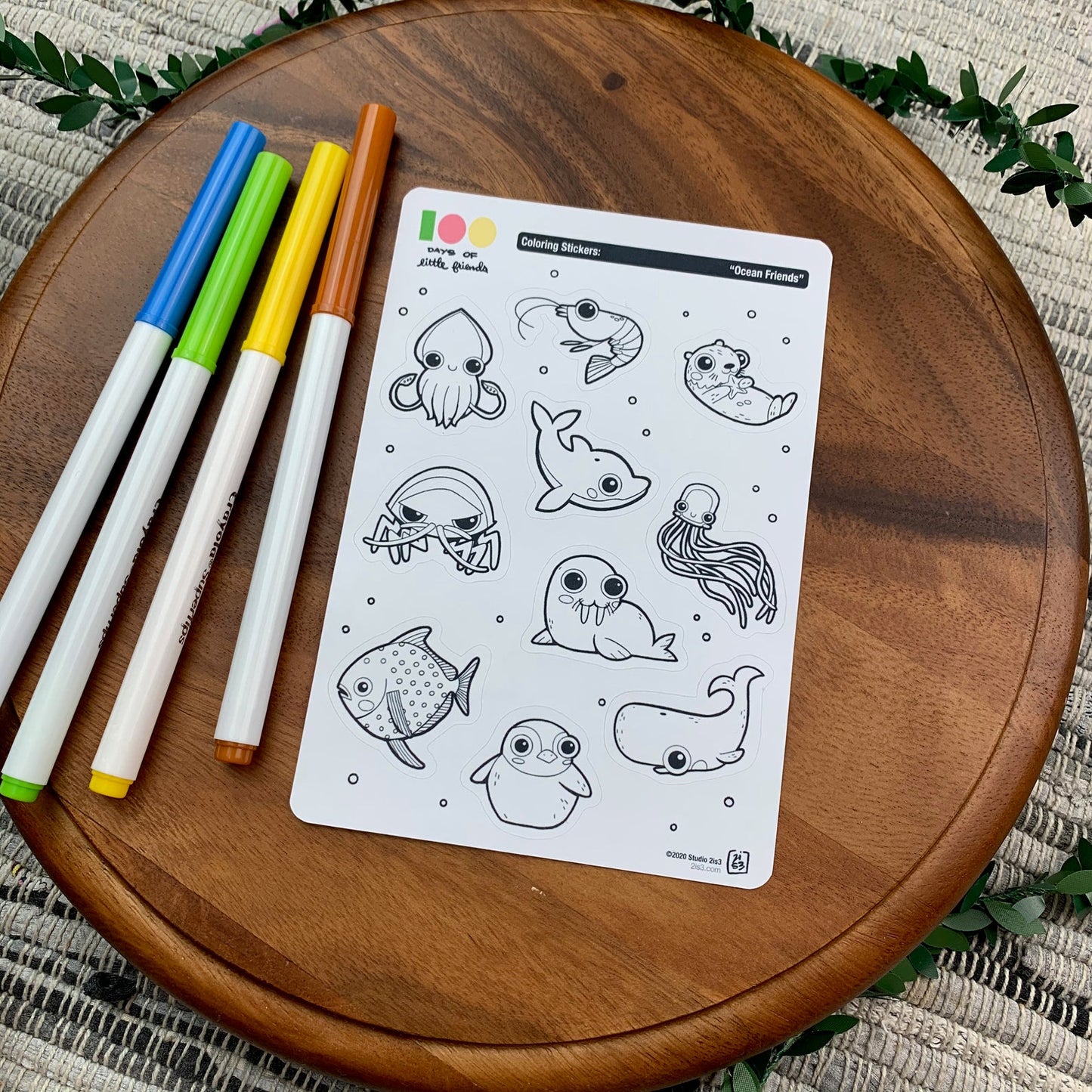 Markers and a sticker sheet with 10 little animal stickers on it. A Squid, Shrimp, Otter, Dolphin, Isopod, Walrus, Jellyfish, Opah, Penguin, and Whale.