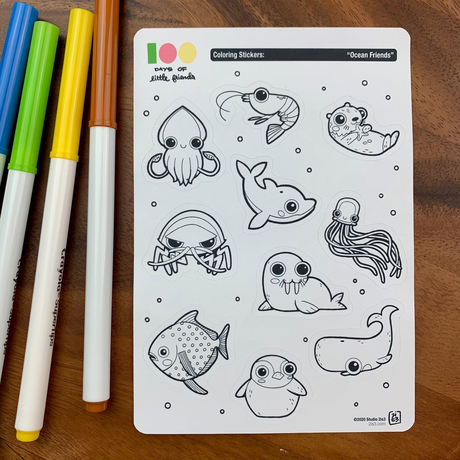 Markers and a sticker sheet with 10 little animal stickers on it. A Squid, Shrimp, Otter, Dolphin, Isopod, Walrus, Jellyfish, Opah, Penguin, and Whale.