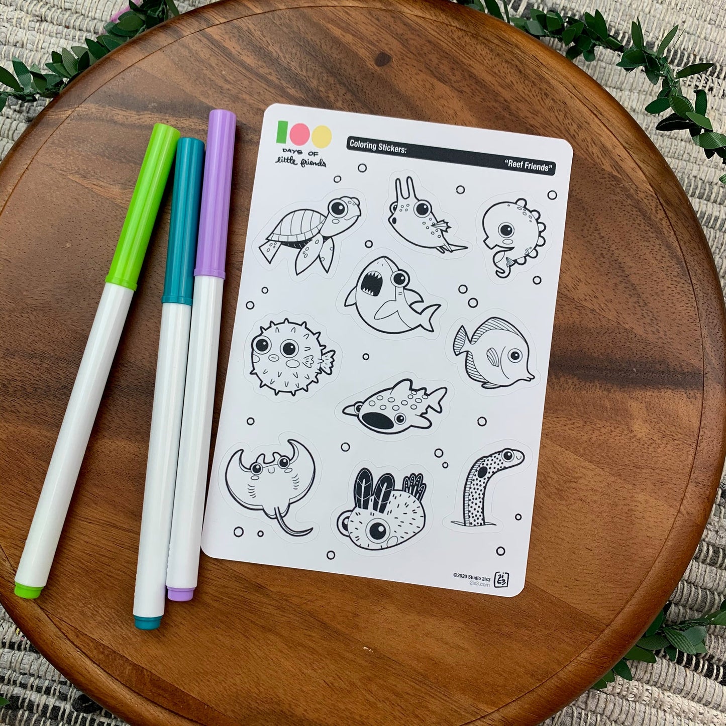 Markers and a sticker sheet with 10 little animal stickers on it. A Sea Turtle, Cowfish, Seahorse, Shark, Pufferfish, Whale Shark, Tang, Ray, Nudibranch, and Garden Eel.