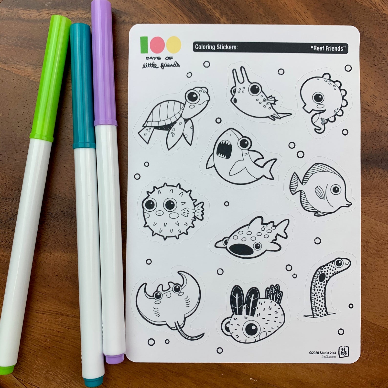 Markers and a sticker sheet with 10 little animal stickers on it. A Sea Turtle, Cowfish, Seahorse, Shark, Pufferfish, Whale Shark, Tang, Ray, Nudibranch, and Garden Eel.