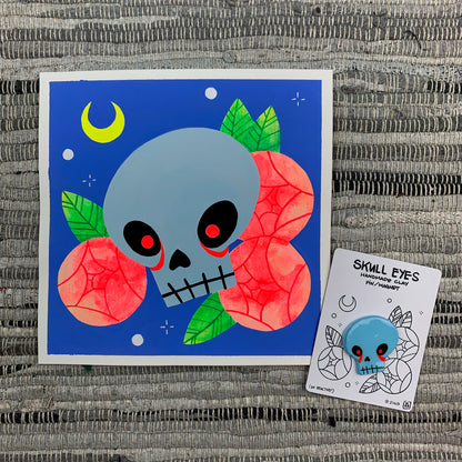 Gouache painting of a skull with glowing red eyes with matching handmade clay pin.