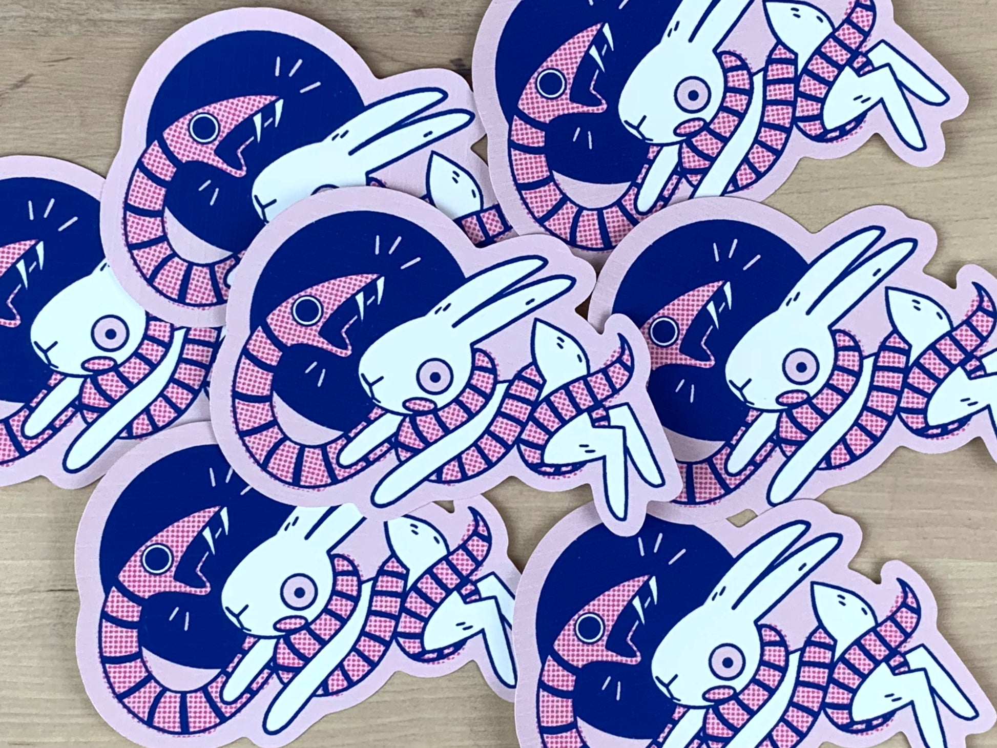 Stickers in pink and blue of a snake wrapping itself around a scared hare/rabbit.