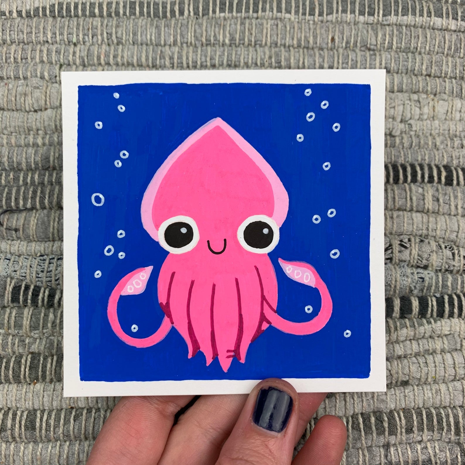 Original artwork of a cute pink squid on a deep blue background with some bubbles. Materials used: Uni-Posca paint markers.