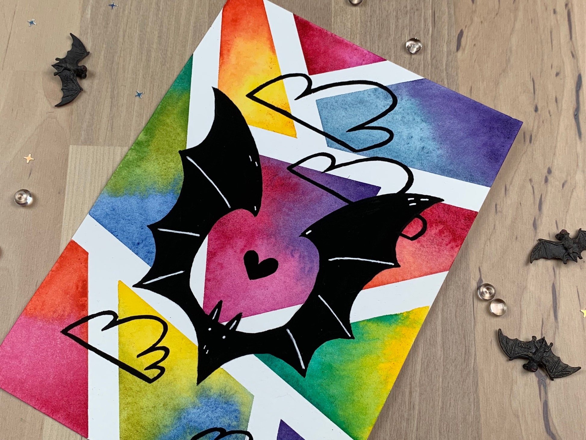 Original artwork depicting a colorful geometric watercolor and gouache painting of a bat.