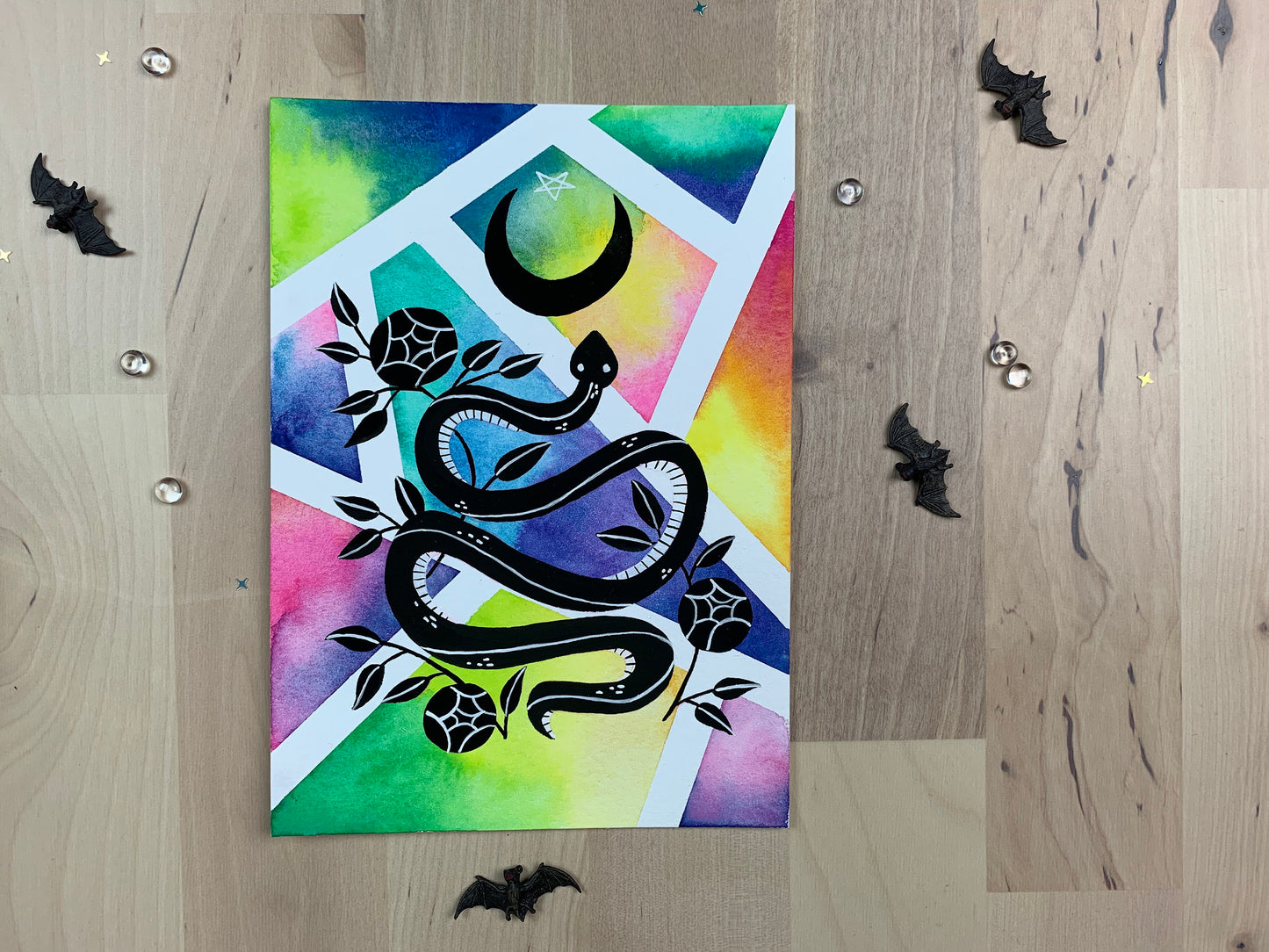 Original artwork depicting a colorful geometric watercolor and gouache painting of a snake with roses and a crescent moon.