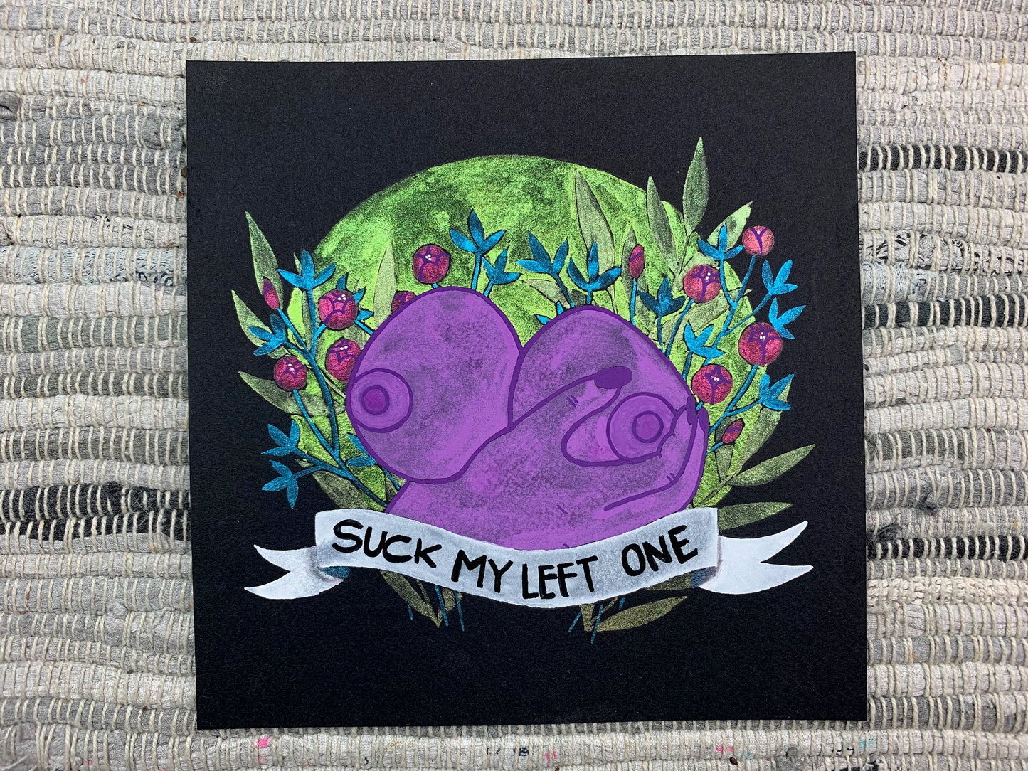A painting of a pair of breasts and a hand holding one of them with a bouquet of color shifting flowers behind it and a banner that says "Suck my left one" in front.