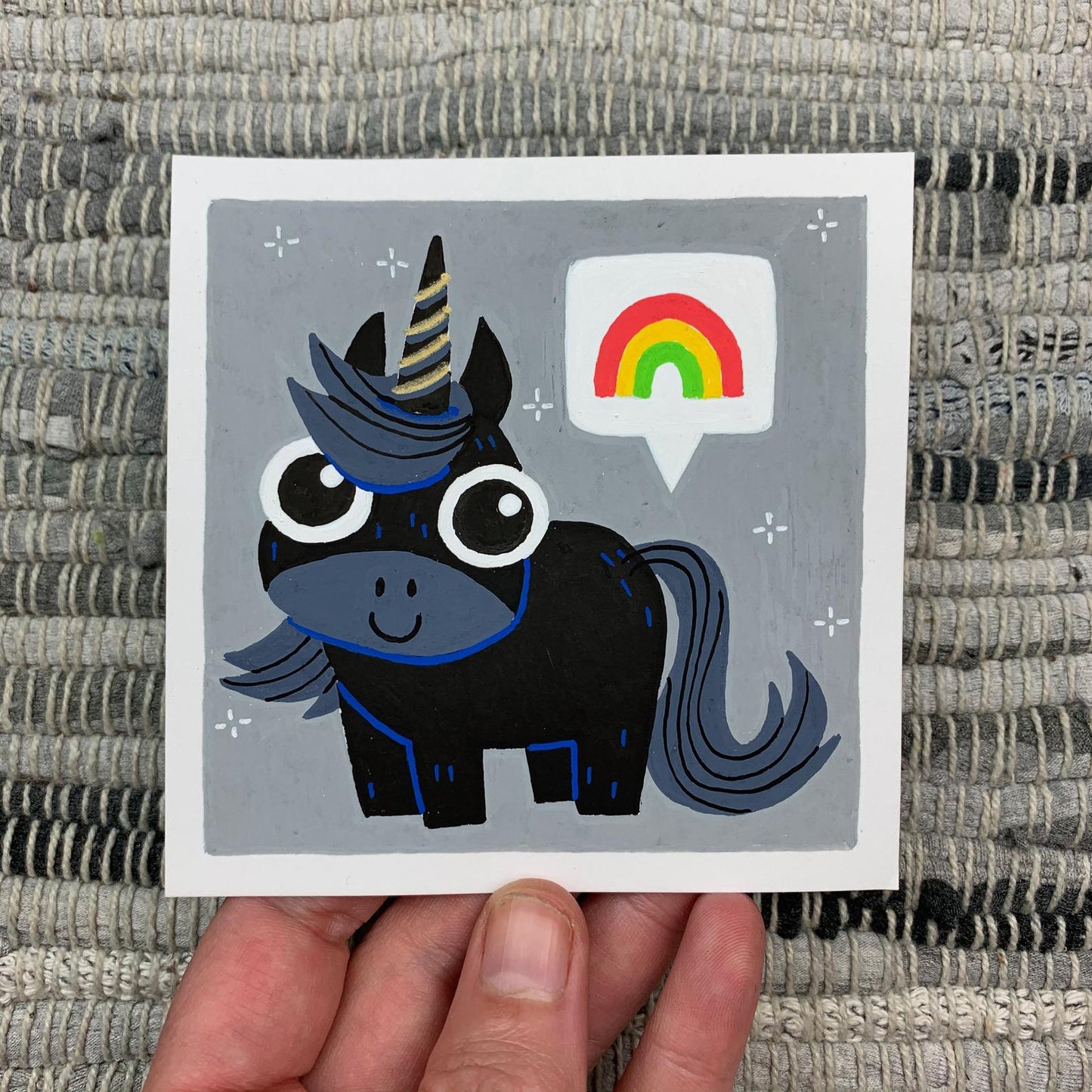 Original artwork of a cute black uicorn with a rainbow in speech bubble. Materials used: Uni-Posca paint markers and a gold gel pen.