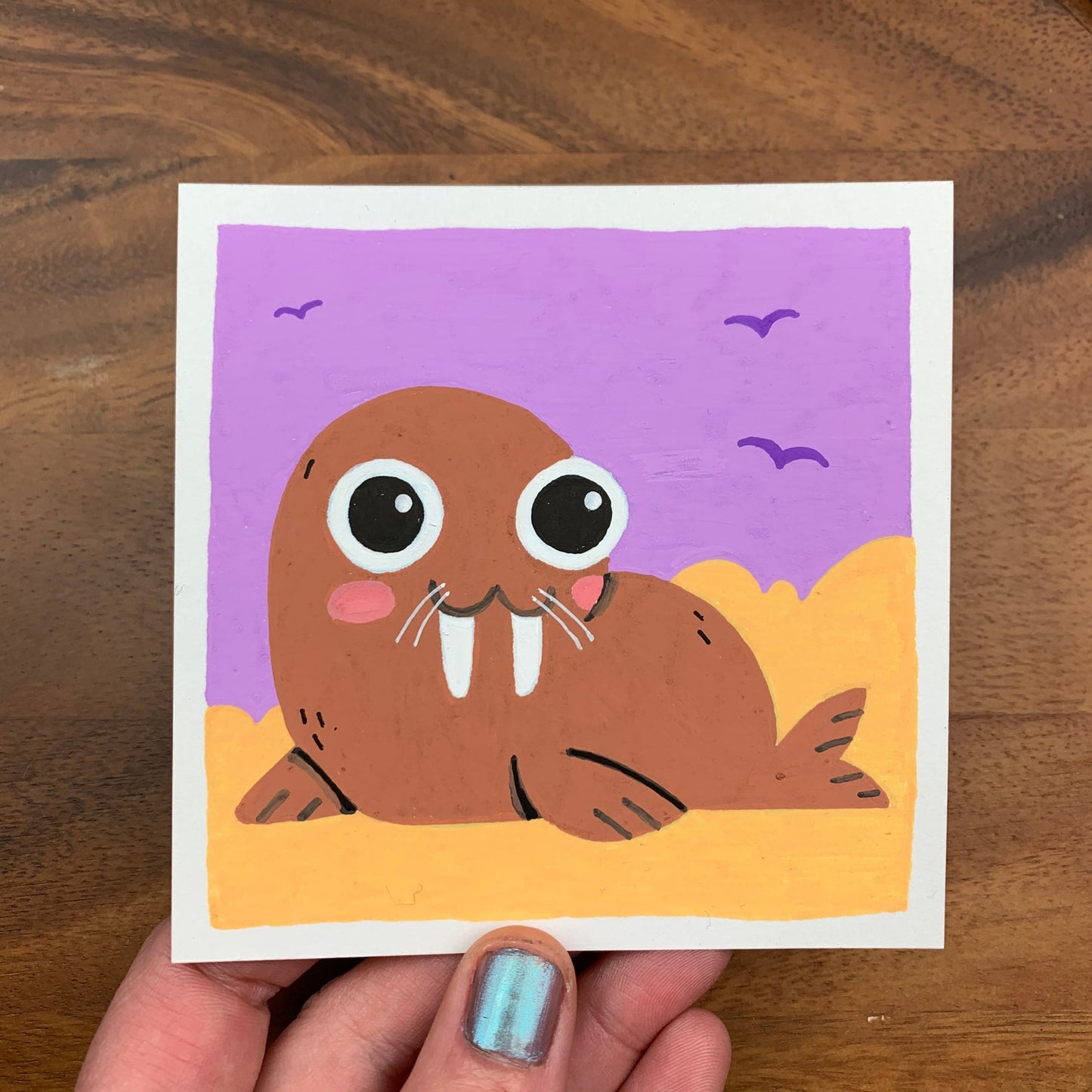 Original artwork of a cute walrus on a beach with a purple sky and seagulls in the background. Materials used: Uni-Posca paint markers.